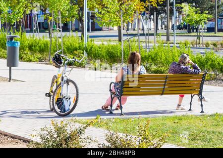 Rückansicht von zwei Frauen mittleren Alters auf Bank sitzen, Fahrrad-Fahrrad in der Nähe geparkt, Sopron, Ungarn Stockfoto