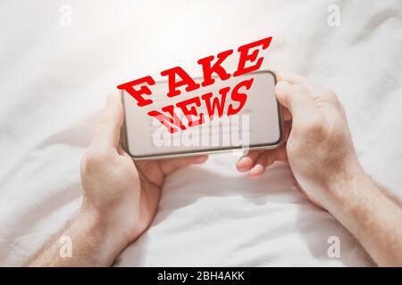 Fake News Infosemics during Covid-19 Pandemie Concept. Mann hält Handy und liest zu Hause Nachrichten oder soziale Netzwerke. Letzte News lesen upd Stockfoto