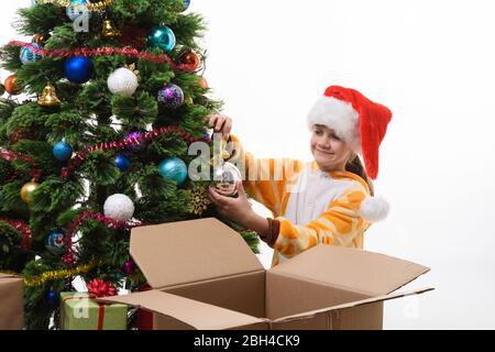 Mädchen hängt einen Weihnachtsball auf dem Weihnachtsbaum Stockfoto