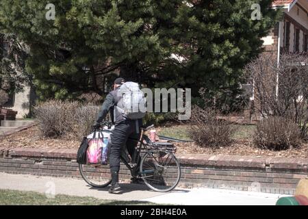 Mann auf Fahrrad mit Paketen beladen. Während der Pandemie von Covid-19 könnte es Obdachlos sein oder Nahrungsmittel und Vorräte liefern. St. Paul Minnesota, USA Stockfoto