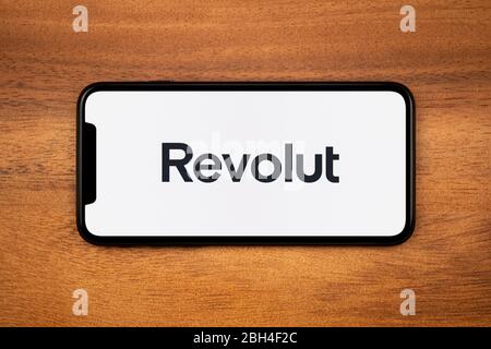 Ein Smartphone mit dem Revolut-Logo liegt auf einem einfachen Holztisch (nur für redaktionelle Zwecke). Stockfoto