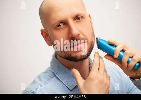 Der Mensch trimmt seinen Bart mit einer elektrischen Schreibmaschine Stockfoto