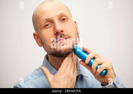 Der Mensch trimmt seinen Bart mit einer elektrischen Schreibmaschine Stockfoto