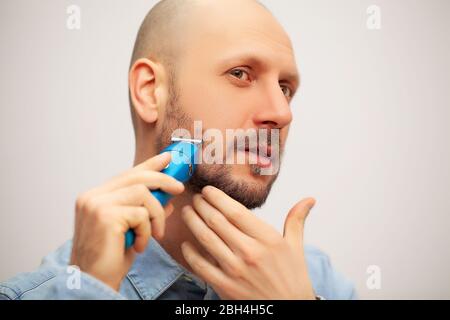 Der Mensch trimmt seinen Bart mit einer elektrischen Schreibmaschine Stockfoto