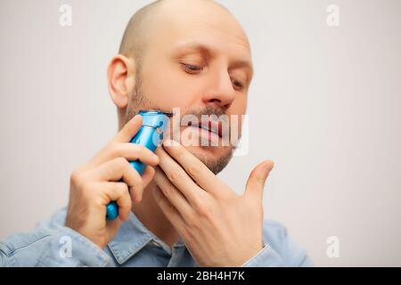 Der Mensch trimmt seinen Bart mit einer elektrischen Schreibmaschine Stockfoto