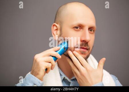 Der Mensch trimmt seinen Bart mit einer elektrischen Schreibmaschine Stockfoto