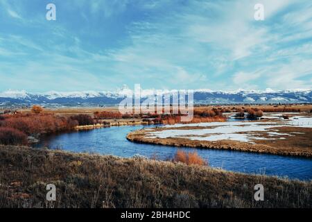 Malerischer Blick auf die schneebedeckte Teton-Bergkette mit einem gewundenen Fluss im Vordergrund. Tetonia, Idaho. Teton landschaftlich schöne Nebenstraße Stockfoto