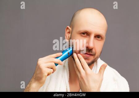 Der Mensch trimmt seinen Bart mit einer elektrischen Schreibmaschine Stockfoto
