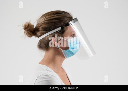 Eine Frau trägt einen Gesichtsschutz, der von einer freiwilligen Initiative hergestellt wurde, die während der Coronavirus-Pandemie im Vereinigten Königreich PSA liefern soll. Stockfoto