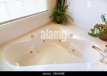 Neues sauberes Haus Hotel oder Appartement Bad Badezimmer Innenausstattung mit niemand und über Blick auf Badewanne Badewanne Whirlpool durch Fenster und grüne Zimmerpflanzen Stockfoto