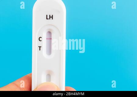 Mann Hand mit der Hand schwanger Test Kit auf blauem Hintergrund. Stockfoto