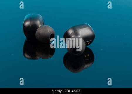 Kabellose Bluetooth-Kopfhörer auf Reflexionsfläche. Stockfoto