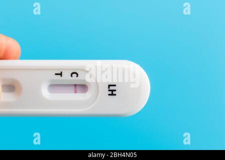 Mann Hand mit der Hand schwanger Test Kit auf blauem Hintergrund. Stockfoto