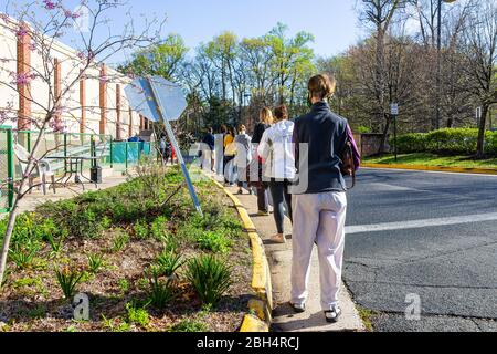 Reston, USA - 9. April 2020: Soziale Distanz von Menschen, die in der Warteschlange warten, durch Trader Joe's Lebensmittelgeschäft aufgrund der Begrenzung für Kunden im Geschäft während Stockfoto