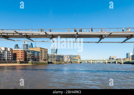 London, Großbritannien - 22. Juni 2018: Menschen, die auf der Millennium Brücke der Stadt spazieren, mit Fußgängern, die die Themse überqueren und die Skyline der Stadt betrachten Stockfoto