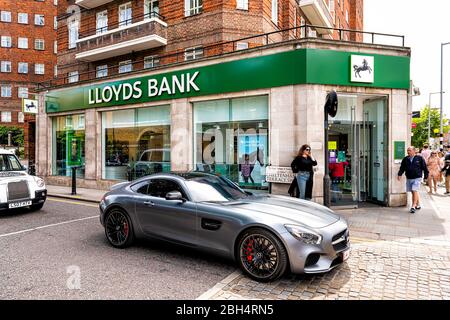 London, Großbritannien - 23. Juni 2018: Grünes Lloyds Bank Schild auf Zweigniederlassung Gebäude in der Stadt mit Ziegelarchitektur und Diplomat Auto im gehobenen Chelsea nahe Stockfoto