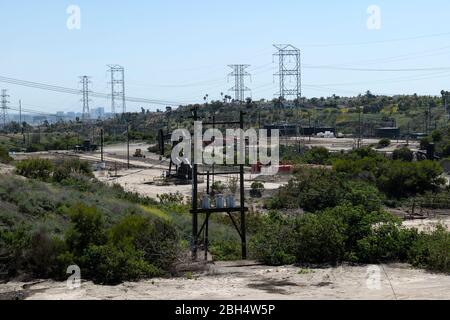 Pumpenheber, Lagertanks und Hochspannungsleitungen in einem Ölfeld Stockfoto