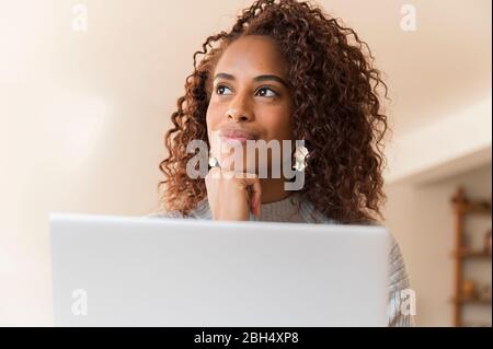 Frau, die hinter dem Laptop denkt Stockfoto