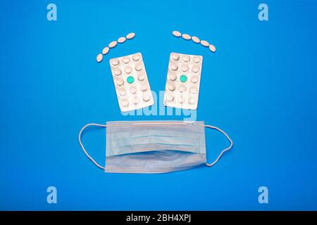 Gesicht einer weißen medizinischen Maske und zwei Blasen von Tabletten Stockfoto