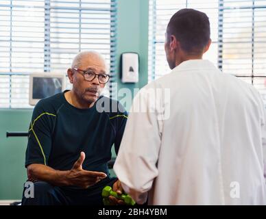 Älterer Mann im Rehabilitationszentrum im Gespräch mit dem Arzt Stockfoto