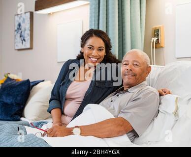 Lächelnde Frau und älterer Mann im Bett Stockfoto
