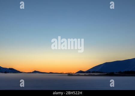 Schneebedecktes Feld und Berg bei Sonnenuntergang Stockfoto