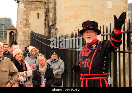 LONDON, ENGLAND, 13. MÄRZ: Ein Yeoman Warder in zeitgekleideter Kleidung führt Besucher auf eine Tour durch den Tower of London am 13. März 2020 in London, Großbritannien Stockfoto