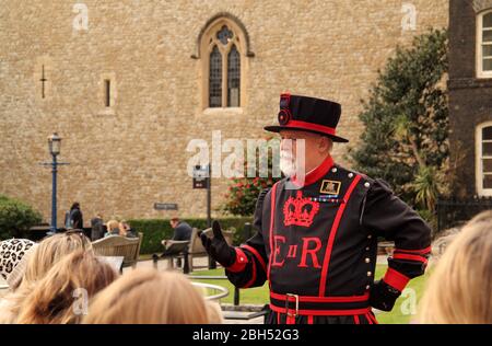 LONDON, ENGLAND, 13. MÄRZ: Ein Yeoman Warder in zeitgekleideter Kleidung führt Besucher auf eine Tour durch den Tower of London am 13. März 2020 in London, Großbritannien Stockfoto