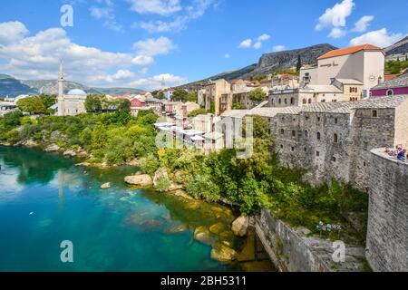 Ein Blick auf die alte Stadt Mostar, Bosnien mit seiner Altstadt, Cafés am Fluss, Minarette und Moscheen von der alten Brücke über den Fluss Neretva genommen. Stockfoto