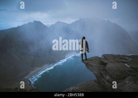 Mann mit Kamera auf einer Klippe am Ryten-Berg auf den Lofoten-Inseln, Norwegen Stockfoto