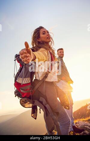 Menschen helfen sich gegenseitig, bei Sonnenaufgang einen Berg hinauf zu wandern. Stockfoto