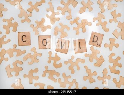 Eine Ansicht von Puzzleteilen, die gekachelte Buchstaben umgeben, die das Wort COVID-19 schreiben. Stockfoto