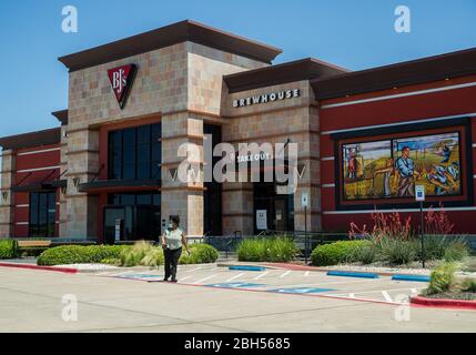 Round Rock, Texas, USA. 23. April 2020. Ein BJ's Brewhouse Mitarbeiter geht zu einem Kundenfahrzeug, um eine Quittung mit einer Maske an in Round Rock zu liefern Premium Outlet Center ist für das Essen geschlossen und akzeptiert nur Take-out und Lieferaufträge in Round Rock, Texas. Matthew Lynch/CSM/Alamy Live News Stockfoto