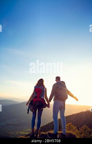 Wanderer mit Rucksack entspannend auf einem Berg und genießen den Blick auf das Tal Stockfoto