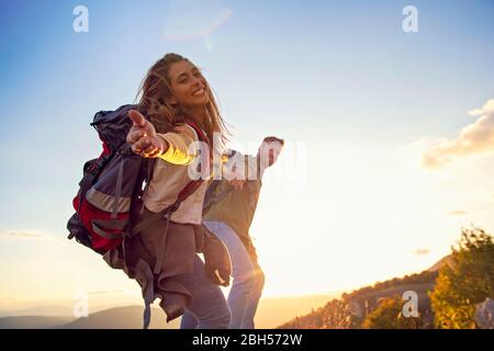 Menschen helfen sich gegenseitig, bei Sonnenaufgang einen Berg hinauf zu wandern. Stockfoto