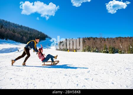 Junge Glücklich Paar Auf Schlitten Spaß Haben Stockfoto