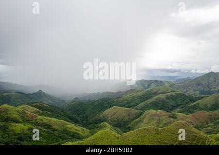 Faszinierende Berglandschaft in Zentral-Panama, mit dichten Wolken, die den Himmel umhüllen und sanftem Regen, der über die grünen Hügel fällt. Stockfoto