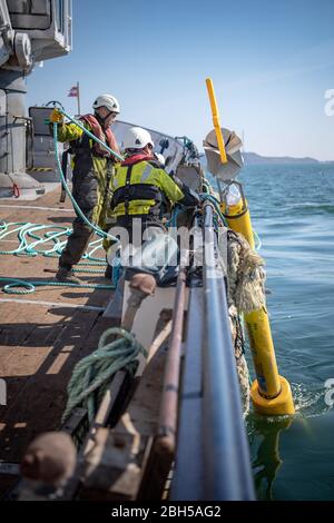 23. April 2020, Schleswig-Holstein, Helgoland: Eine Tonne wird ins Wasser gelassen. Startschuss für ein großes maritimes Testfeld vor Helgoland: Wissenschaftler des Testzentrums für Maritime Technologien haben in Tonnen eine Fläche von drei Millionen Quadratmetern unweit der Nordseeinsel markiert. Es soll künftig Testeinrichtungen für die maritime Robotik bereitstellen. Hersteller und Wissenschaftler können dort verschiedene Szenarien testen. So können beispielsweise autonome Unterwasserfahrzeuge für Offshore-Windenergieanlagen unter realen Bedingungen im Meer getestet werden oder Drohnen, die über das Wasser fliegen, für in Stockfoto