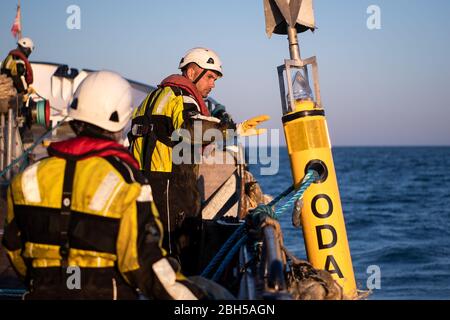23. April 2020, Schleswig-Holstein, Helgoland: Eine Tonne wird ins Wasser gelassen. Startschuss für ein großes maritimes Testfeld vor Helgoland: Wissenschaftler des Testzentrums für Maritime Technologien haben in Tonnen eine Fläche von drei Millionen Quadratmetern unweit der Nordseeinsel markiert. Es soll künftig Testeinrichtungen für die maritime Robotik bereitstellen. Hersteller und Wissenschaftler können dort verschiedene Szenarien testen. So können beispielsweise autonome Unterwasserfahrzeuge für Offshore-Windenergieanlagen unter realen Bedingungen im Meer getestet werden oder Drohnen, die über das Wasser fliegen, für in Stockfoto