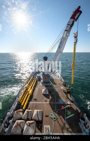 23. April 2020, Schleswig-Holstein, Helgoland: Mit Hilfe eines Krans wird eine Tonne ins Wasser abgelassen. Startschuss für ein großes maritimes Testfeld vor Helgoland: Wissenschaftler des Testzentrums für Maritime Technologien haben in Tonnen eine Fläche von drei Millionen Quadratmetern unweit der Nordseeinsel markiert. Es soll künftig Testeinrichtungen für die maritime Robotik bereitstellen. Hersteller und Wissenschaftler können dort verschiedene Szenarien testen. So können beispielsweise autonome Unterwasserfahrzeuge für Offshore-Windenergieanlagen unter realen Bedingungen im Meer oder Drohnen flyi getestet werden Stockfoto