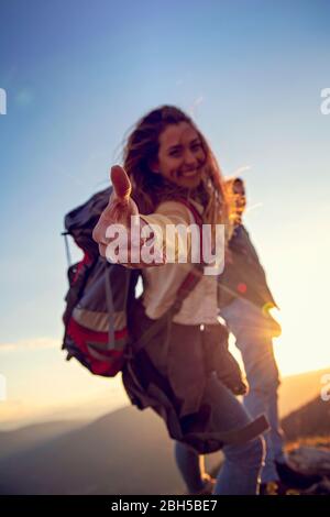 Menschen helfen sich gegenseitig, bei Sonnenaufgang einen Berg hinauf zu wandern. Stockfoto