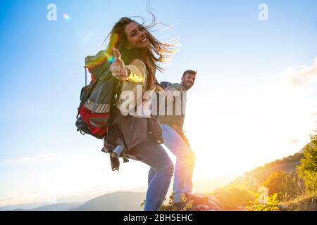 Menschen helfen sich gegenseitig, bei Sonnenaufgang einen Berg hinauf zu wandern. Stockfoto