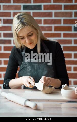 Glückliche Frau macht Keramik-Keramik, Hahn mit Spatel. Konzept für Frau in freiberuflicher, geschäftlicher. Handwerkliches Produkt. Verdienen Sie mehr Geld, Side Hustle Stockfoto