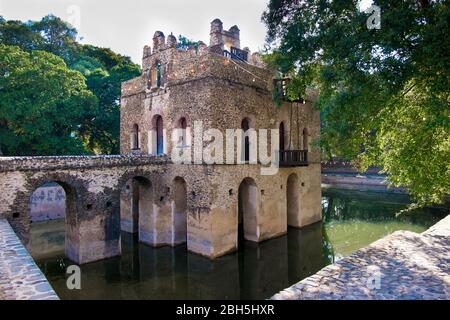 Ein gefüllter Wassertank zeigt eine Reflexion und umgibt das schöne Steingebäude im Zentrum von Fasilides' Bath. In Gondar, Äthiopien, Afrika. Stockfoto