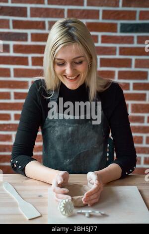 Glücklich lächelnde Frau Herstellung Keramik Keramik, tippen Sie mit Spatel. Konzept für Frau in freiberuflicher, geschäftlicher. Handwerkliches Produkt. Verdienen Sie mehr Geld, Seite Stockfoto