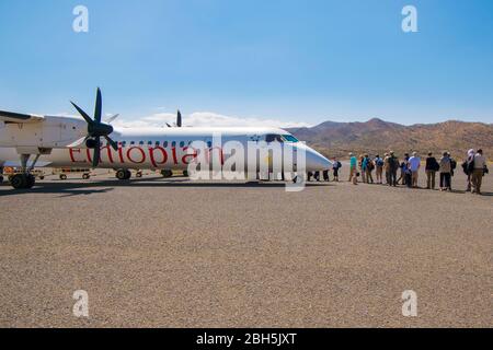 Passagiere stehen auf dem Asphalt und warten darauf, in ein Propellar-Flugzeug von Ethiopian Airlines zu laden. In Lalibella, Äthiopien, Afrika. Stockfoto