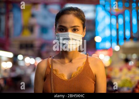 Gesicht der jungen asiatischen Touristen Frau trägt Maske zum Schutz vor Corona-Virus Ausbruch in Chinatown bei Nacht Stockfoto