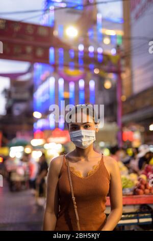 Junge asiatische Touristenfrau trägt Maske zum Schutz vor Corona-Virus Ausbruch in Chinatown bei Nacht Stockfoto