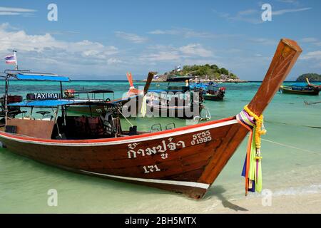 Taxi Boot am Sonnenaufgangsstrand thailand asien, mit klarem blauen Wasser und blauem Himmel, koh Usen Insel im Hintergrund. Stockfoto