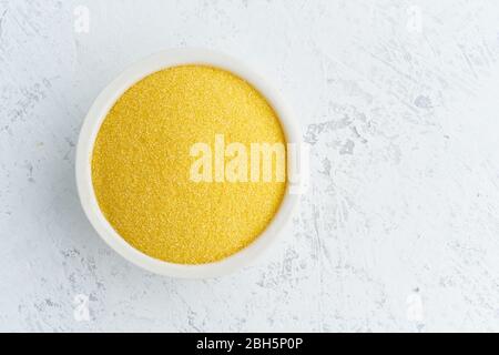 Mais, Polenta in weißer Schale auf weißem Hintergrund. Getrocknetes Getreide in der Tasse, veganes Essen Stockfoto